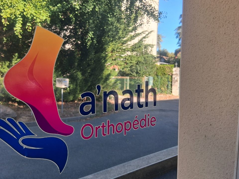 Le logo a'nath-Orthopédie, un pied et une main stylisés, collé sur la vitrine du cabinet.