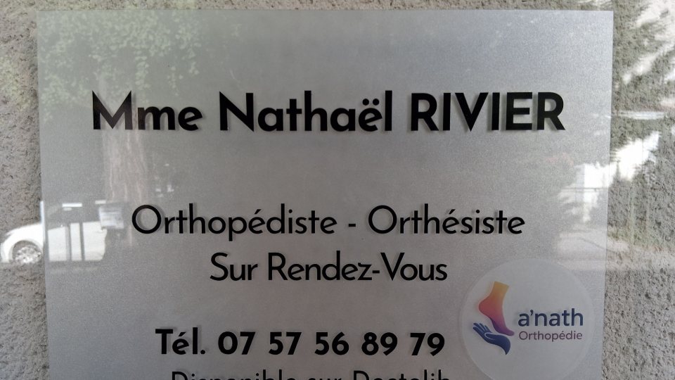 La plaque professionnelle à l'entrée : Mme Nathaël Rivier, orthopédiste-orthésiste, sur rendez-vous, avec le téléphone et la mention « disponible sur Doctolib ».