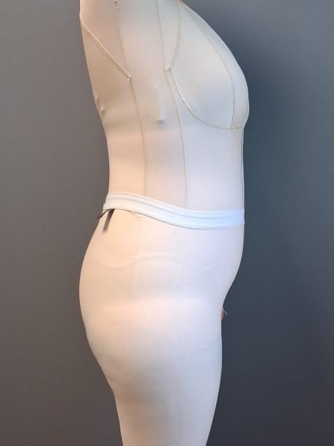 Body compressif couleur chair porté avec un shorty par-dessus, vu de profil.