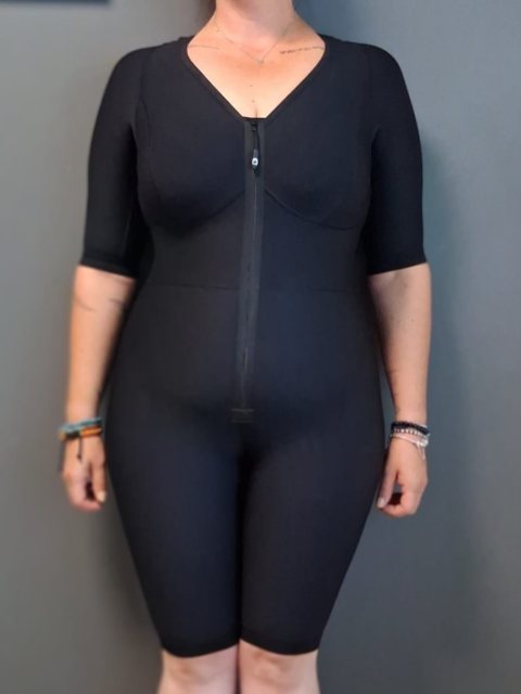 Combinaison compressive noire à manches courtes et jambes courtes, fermée par une glissière sur le devant, portée.